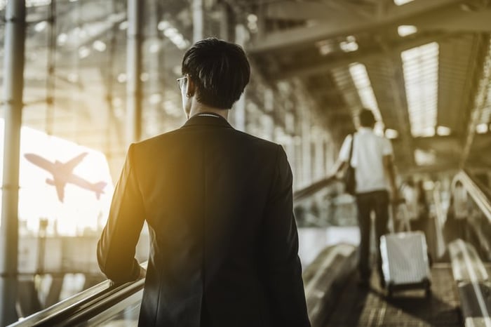 A man with a suitcase walking through a sunny airport.