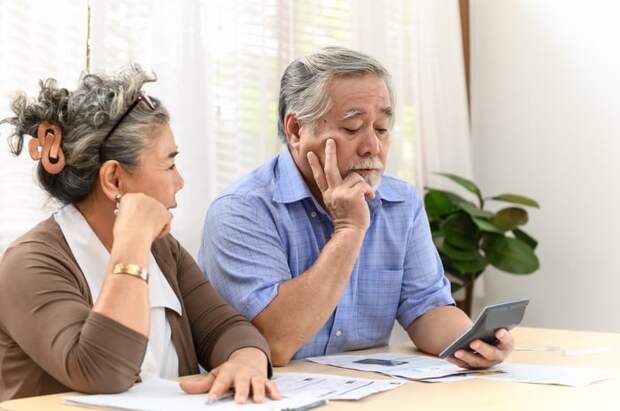A visibly worried couple examining their finances while seated at a table in their home.