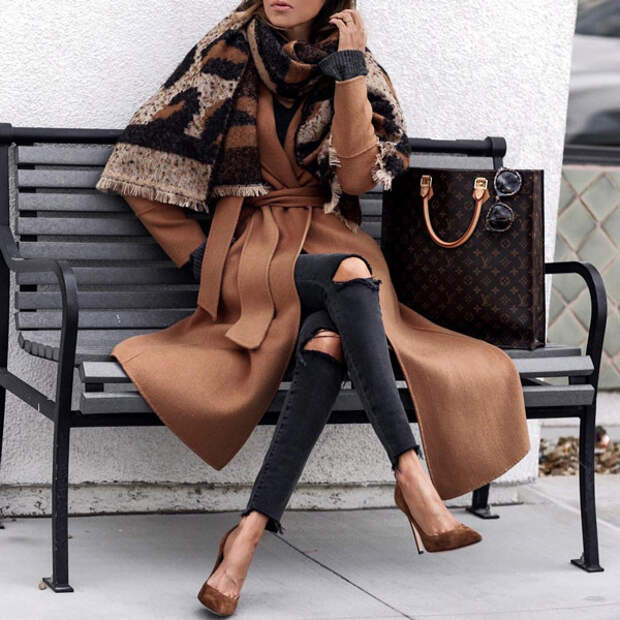 Девушка в серых рванных джинсах, коричневое пальто с поясом и уютный шарф