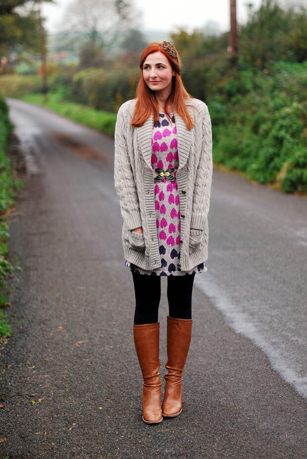 Long cable knit cardigan layered over patterned dress