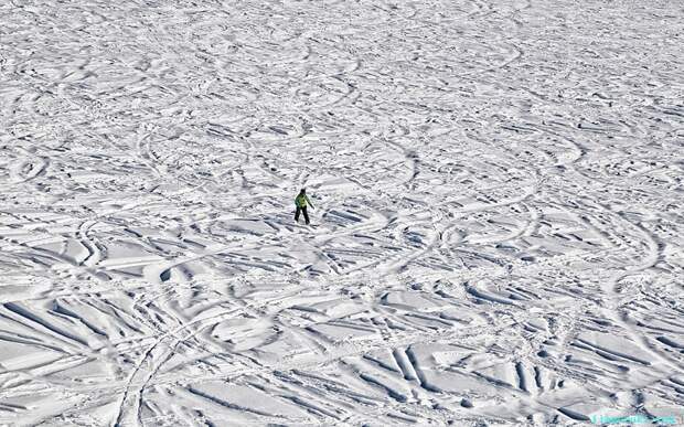 Одинокий сноубордист спускается вниз по склону, который выглядит как гигантский лабиринт.