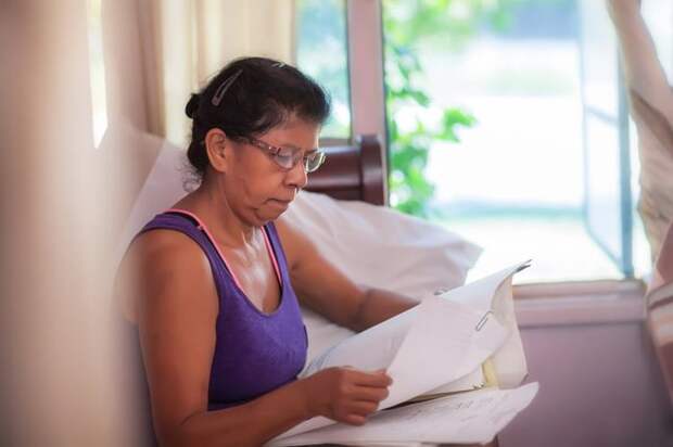 A mature person looks at paperwork on their couch.