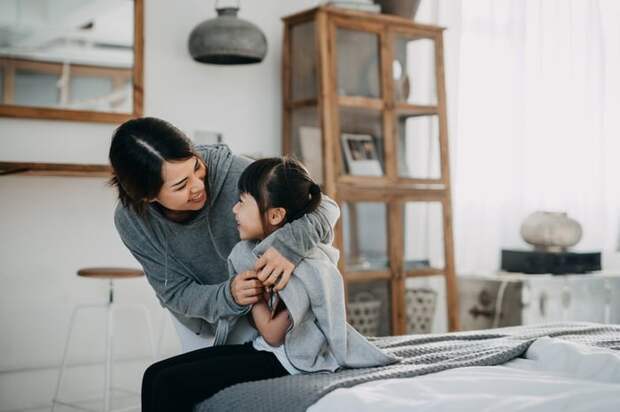 Mother wrapping blanket around young daughter's shoulders.