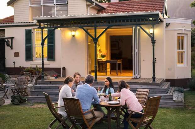 A family of five eating dinner at a backyard patio table.