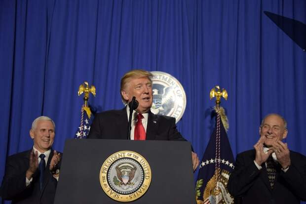 Президент Дональд Трамп выступает с речью перед сотрудниками Департамента национальной безопасности в Вашингтоне. 2017. На заднем плане Майкл Пенс (слева) и Джон Келли (справа)