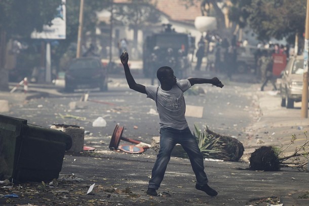 A demonstrator throws a rock towards riot police during a demonstration in Senegal's capital Dakar