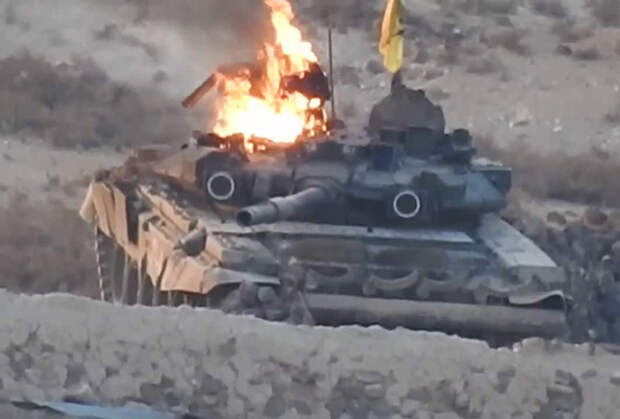 Горящий танк Т-90А со знаменем «Харакат Хезболла ан-Нуджаба» во время боев с «Исламским государством» в районе Ханассера