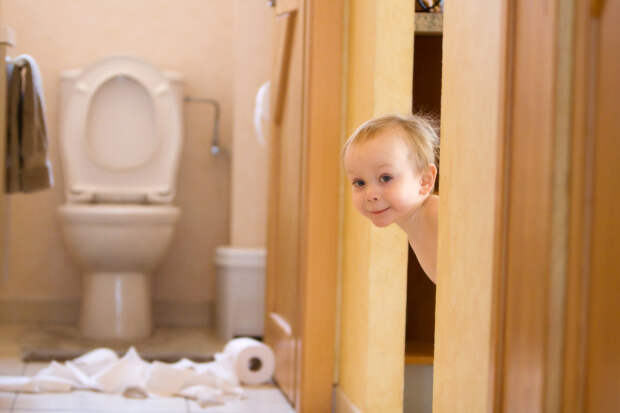 Mischievous toddler boy playing with toliet paper