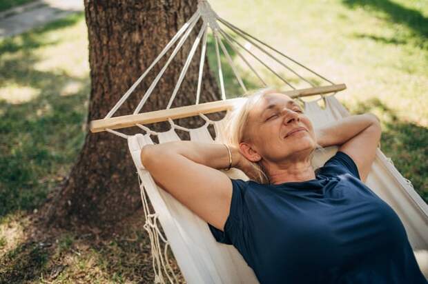 Smiling, relaxed person lying in hammock.