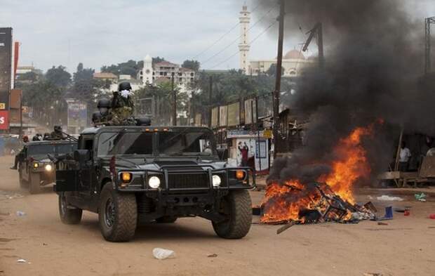 Ugandan military police officers patrol along a barricaded street during demonstrations in Kampala