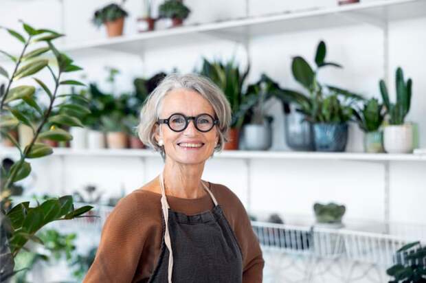 A smiling person standing in front of plants.
