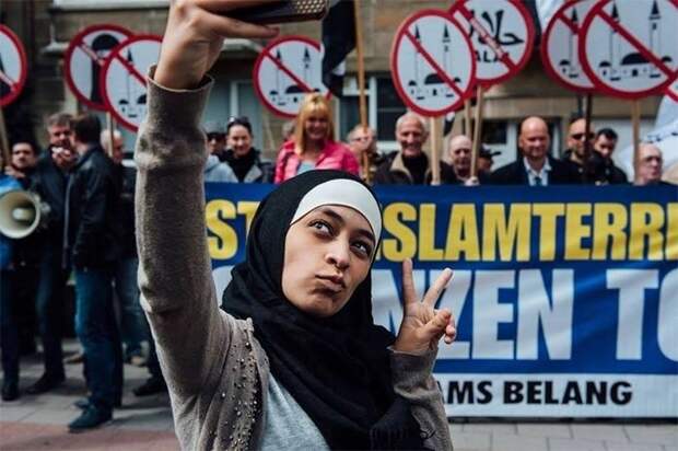 Мусульманка делает селфи на фоне антимусульманской демонстрации в Антверпене, Бельгия, 2016 демонстрации, женщины, кадры, общество, протест, сильные женщины, сильные фотографии, фото