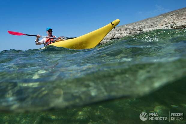 Турист плывет на каяке вдоль берега Черного моря на мысе Тарханкут в Крыму