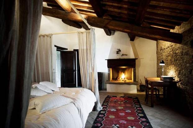 Красивый интерьер спальной с мансардой, что выглядит просто потрясающе благодаря украшению её камином.