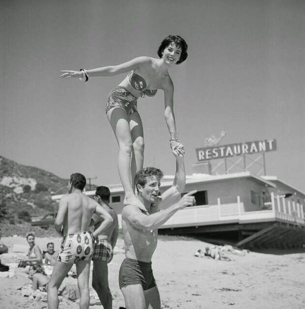 Натали Вуд стоит на плечах Стива Роуланда на пляже Малибу, Калифорния, 15 июля 1956 года. Фото Эрла Лифа звезды, знаменитости, лето, пляж, прошлое, ретро, фотография