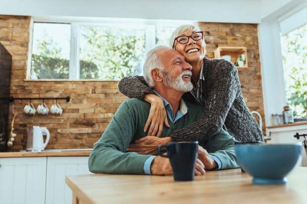 Two people smiling and hugging in kitchen.