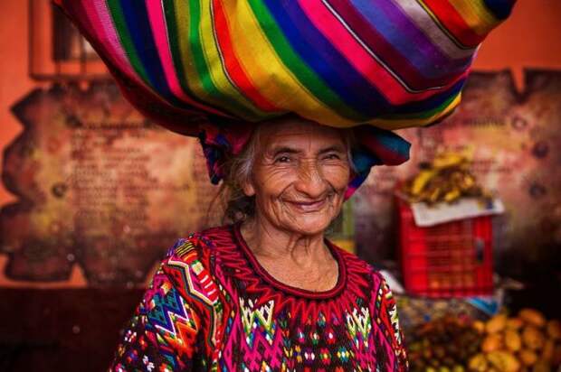 Улыбающаяся женщина переносит груз в небольшом городке Гватемалы.