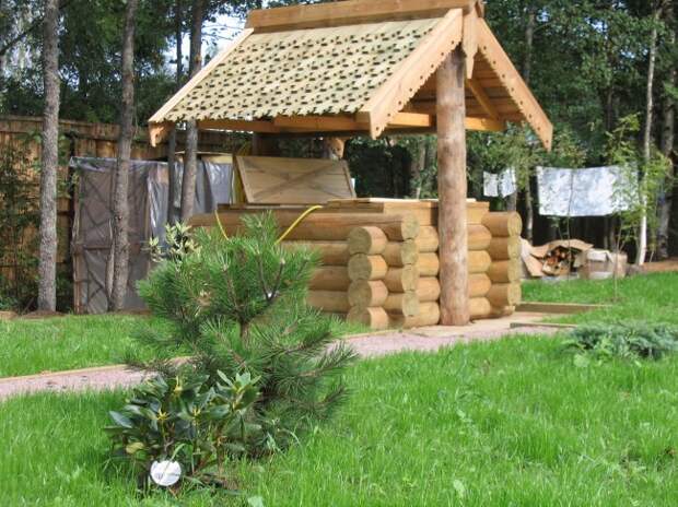 Красивый деревянный домик для колодца с резными элементами