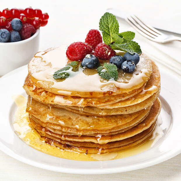 Pile of delicious handmade pancakes topped with honey, raspberri