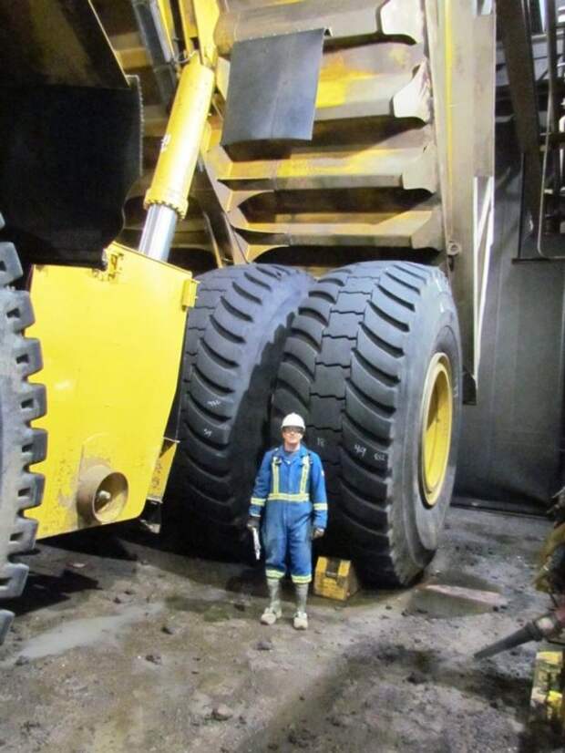 Рабочий на фоне шин 2-го по величине самосвала в мире - Cat 797F