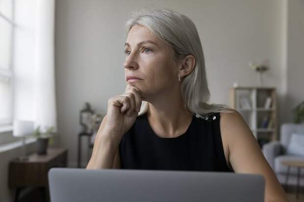 A person deep in thought while sitting at a laptop.