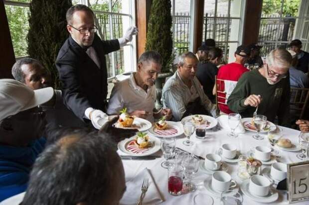 A waiter serves dessert to a table of men listening to Chinese millionaire Chen Guangbiao during a lunch he sponsored for hundreds of needy New Yorkers at Loeb Boathouse in New York's Central Park June 25, 2014. REUTERS/Lucas Jackson