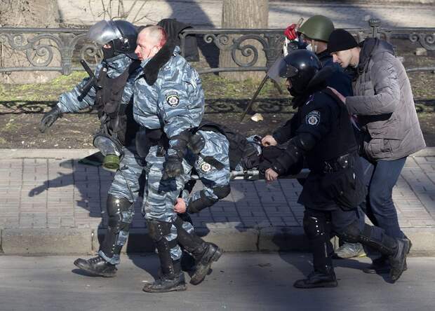 Riot police officers carry their colleague who was injured during clashes with anti-government protesters in Kiev