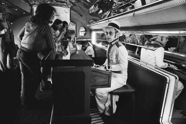Элтон Джон за пианино-баром на борту его личного самолета, 1976 год