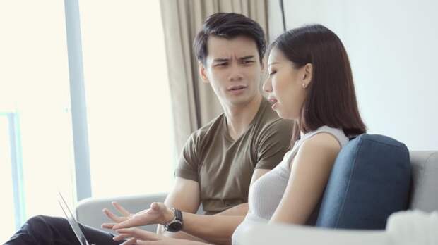 Couple talking while one person gestures to laptop.