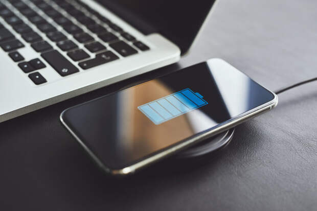 Смартфон во время беспроводной зарядки рядом с ноутбуком