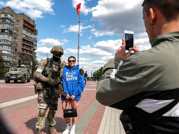 Жители Мелитополя фотографируются с российским солдатом на фоне Знамени Победы, май 2022 года. Фото: EPA/SERGEI ILNITSKY/ТАСС