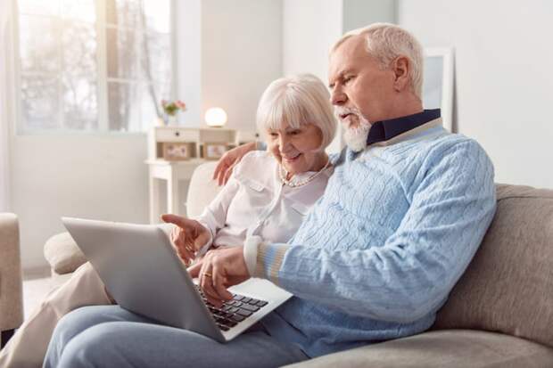 Two people looking at computer on couch.