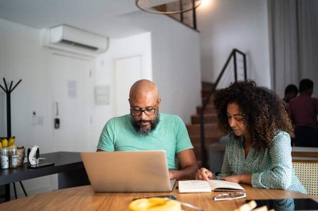 A couple does their personal finances using a laptop and notebook.