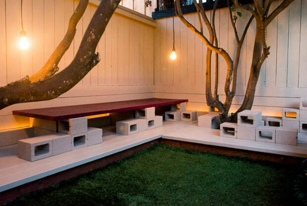 Простая скамейка на территории дачного участка, которую можно создать из нескольких шлакоблоков и деревянной доски.
