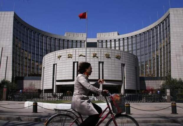 A woman rides past the headquarters of the People's Bank of China, the Chinese central bank, in Beijing, April 3, 2014. REUTERS/Petar Kujundzic