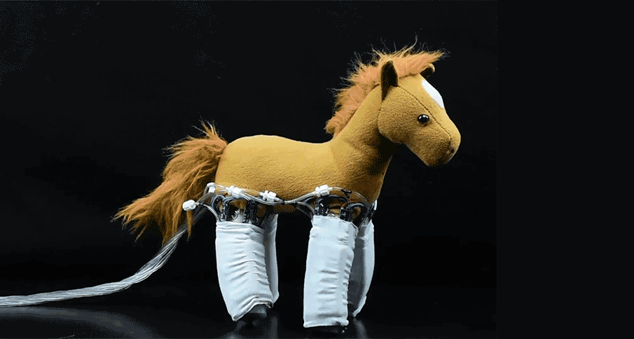 a horse stuffed animal with white wraps around its legs is walking across a the screen against a black background, electric wires trail behind it